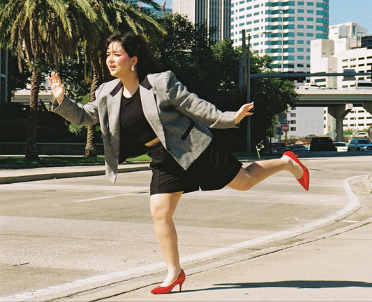 Woman on a city street with palm trees and tall buildings in the background